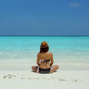 Woman Wearing Black and White Brassiere Sitting on White Sand
